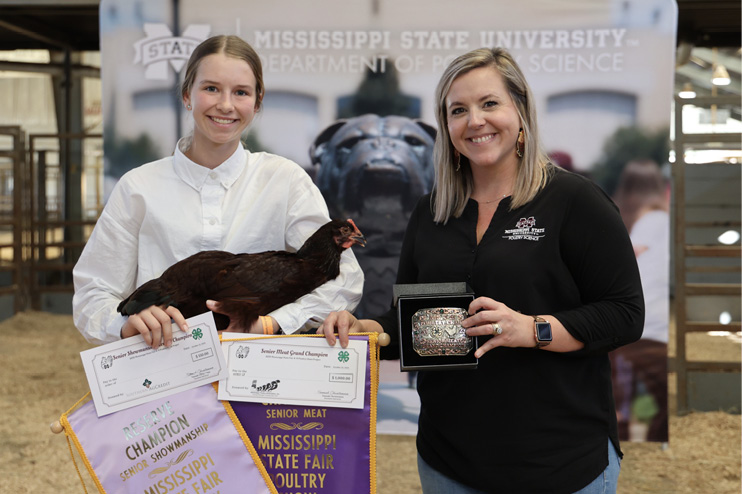 A young girl in a white shirt holds her award-winning bird while accepting her prize.