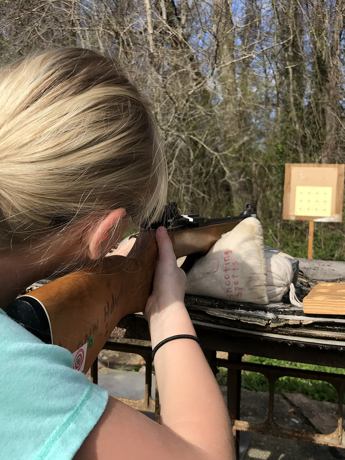 A girl shooting a rifle at a target during a Shooting Sports event.